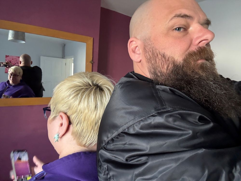 A man and woman stand back to back, you can see in the picture and in the mirror there is a big size differential between the two