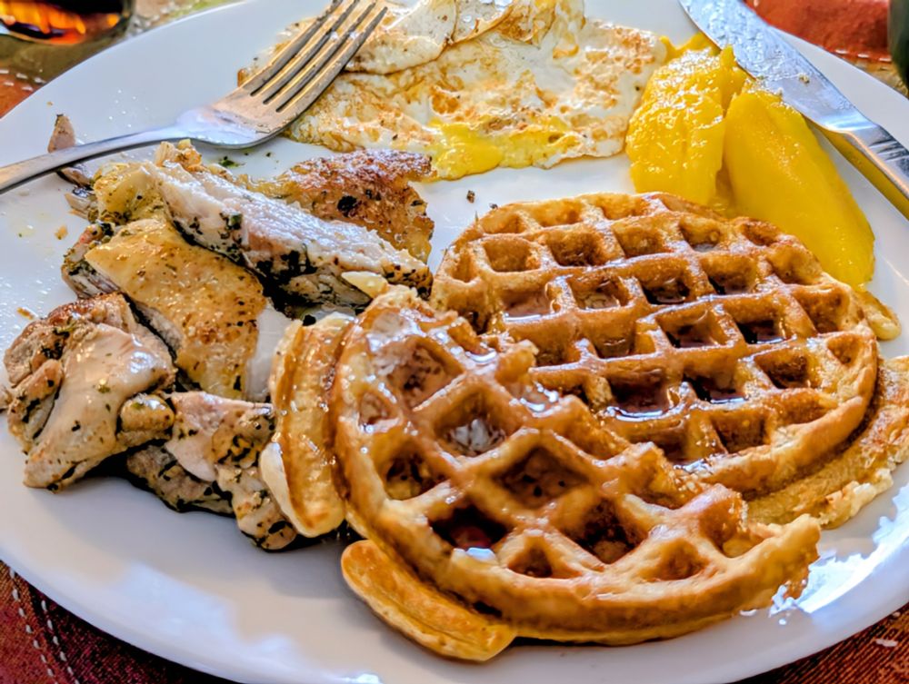 Pan-seared seasoned chicken thigh, homemade buttermilk waffle, egg over well, mango slices.  