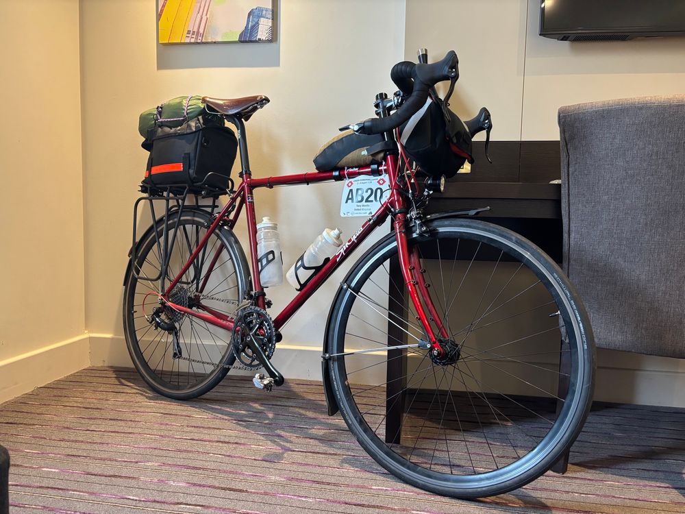 A loaded red bicycle a hotel room with L E L rider plate A B 20.