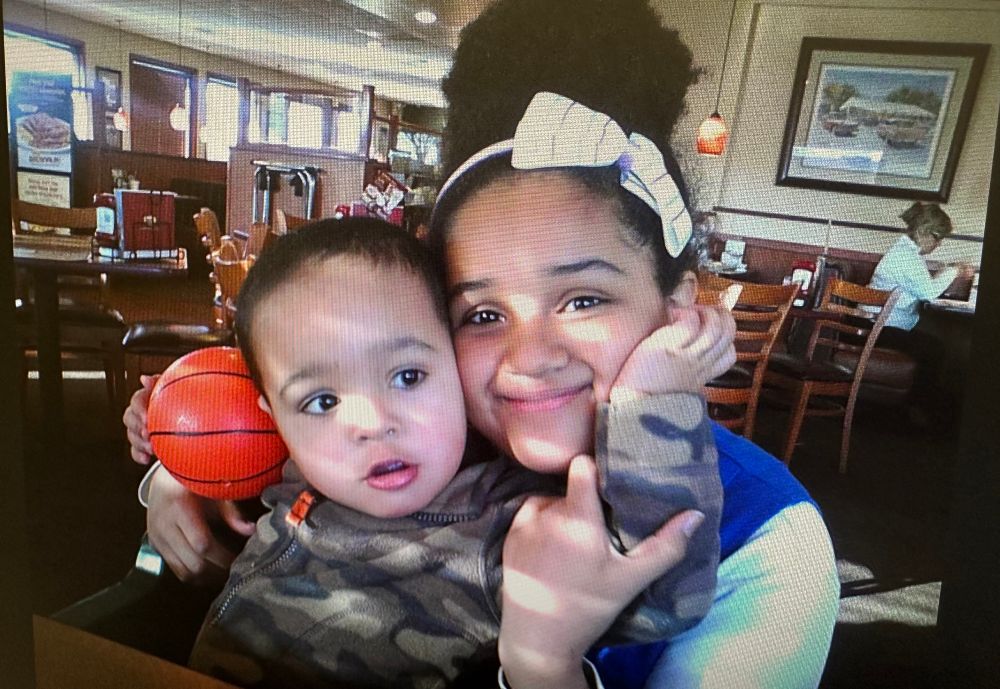 Xavier when he was about three with an 11 year old Jasmine. Xavier is hugging his sister in an embrace and Jazzie smiles proudly. 