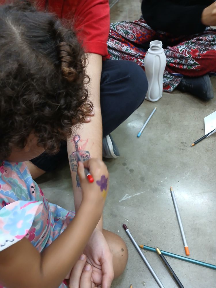Criança pintando tatuagem com lápis de cor