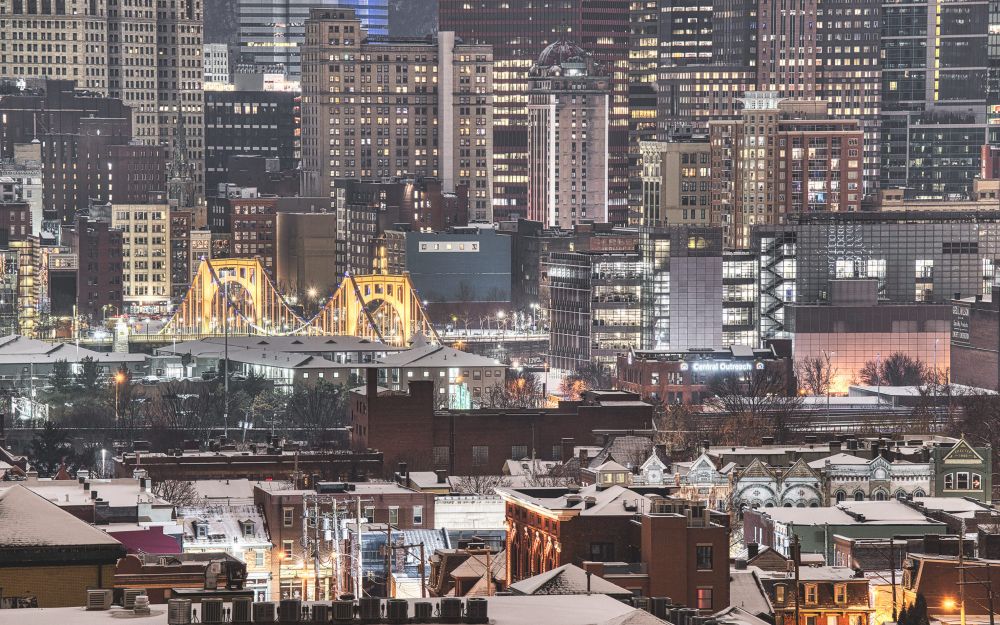 The Rachel Carson bridge raising up from the surrounding buildings on Pittsburghs North shore. In the background are the buildings of downtown 