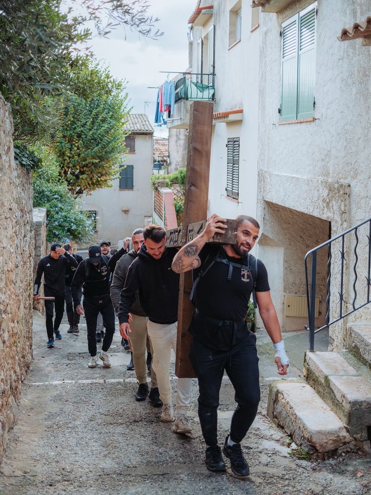 Photo d'hommes en noir, tatoués, portant une croix en bois. 