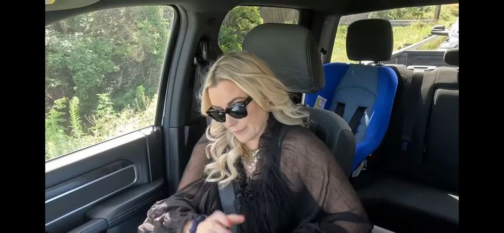 Renee from AEW in a truck with a blue child seat in the back