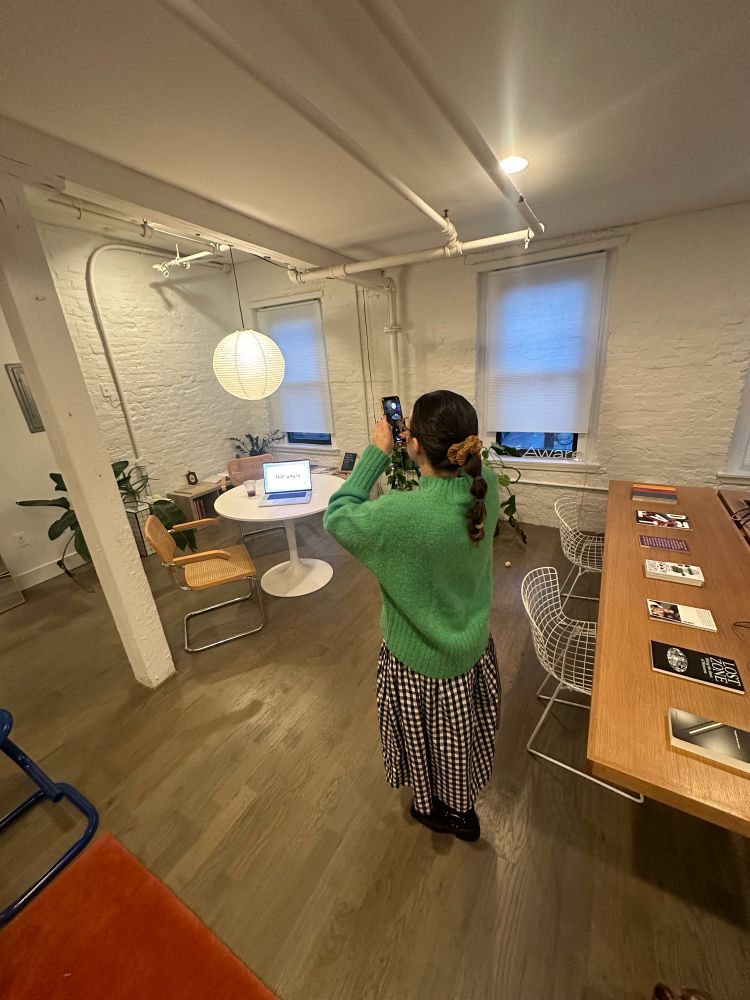 jenny in the studio taking a picture of her laptop displaying a design exploration for a new self aware site