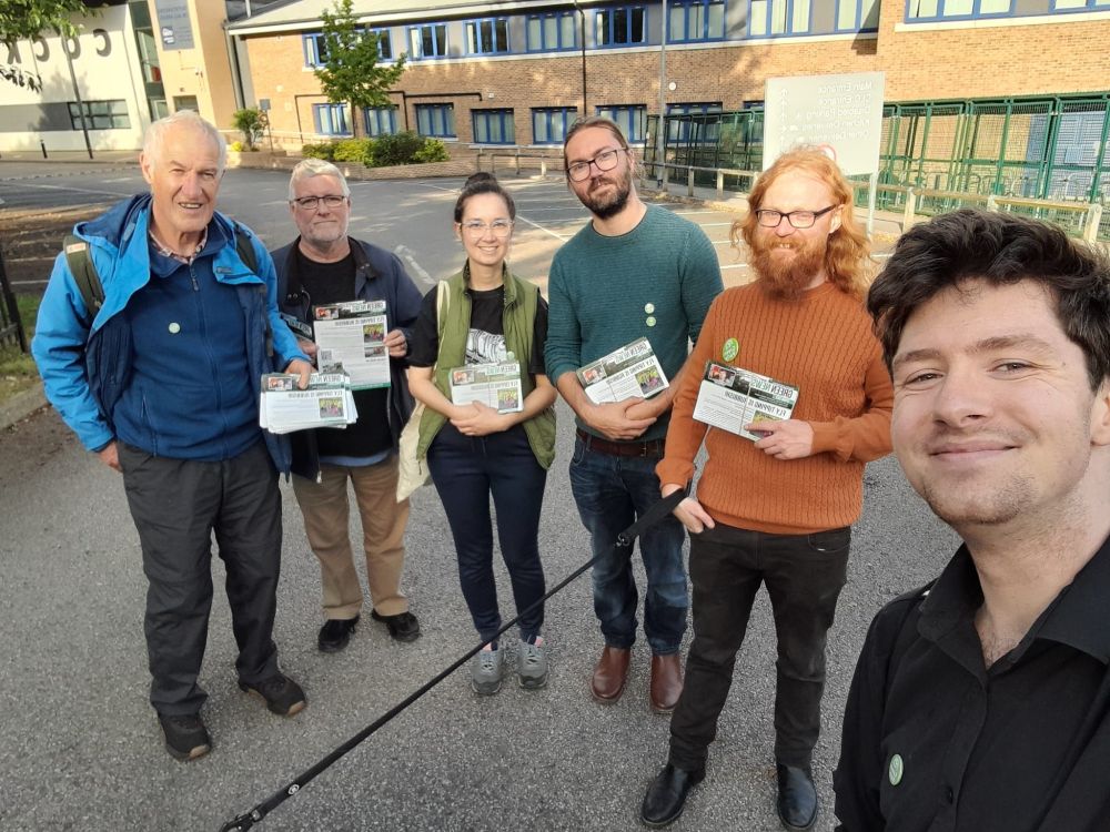 A selfie of Matt with volunteers, holding the latest Green News newsletter.

