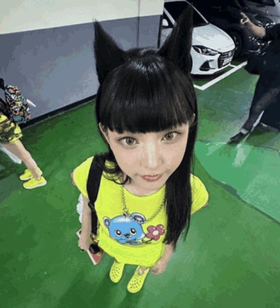 a girl wearing a cat ear headband and a yellow shirt with a teddy bear on it