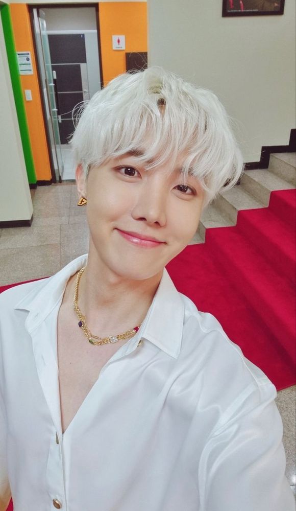 beautiful smiling hobi selca with platinum blonde hair, white shirt and gold earrrings/necklace 