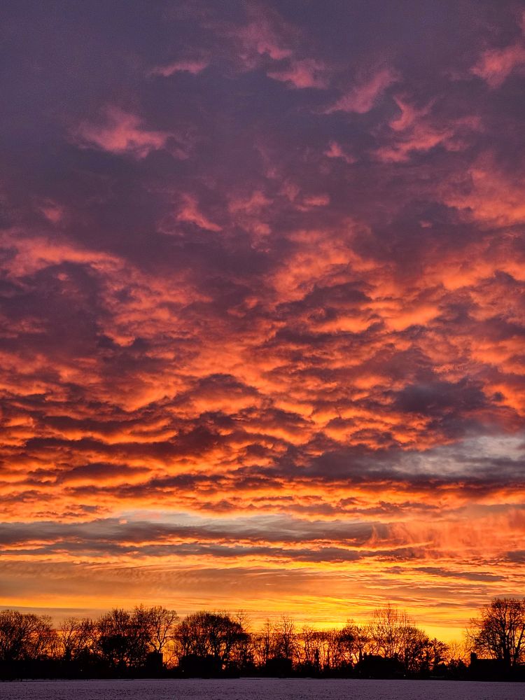 The many fiery colours of a red dawn over a snowy field.