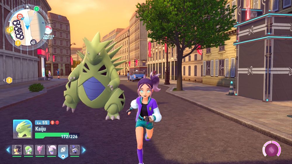 Girl with purple hair in a side ponytail, wearing a black shirt under a purple and white bomber jacket, emerald green shorts, purple socks, and matching tennis shoes. She's running in the street with a massive Pokémon called Kaiju running behind her. It's name is fitting, as it is enormous, green, and spiky. 