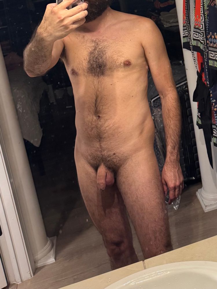 Mirror selfie of a nude make torso. Flaccid, intact penis. 