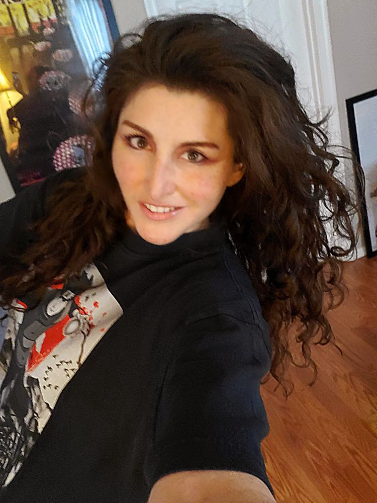 Slight blurry photo of that same woman, but she holding the phone as she walks through her living room and takes a photo. It's cringe, but she is fearless.