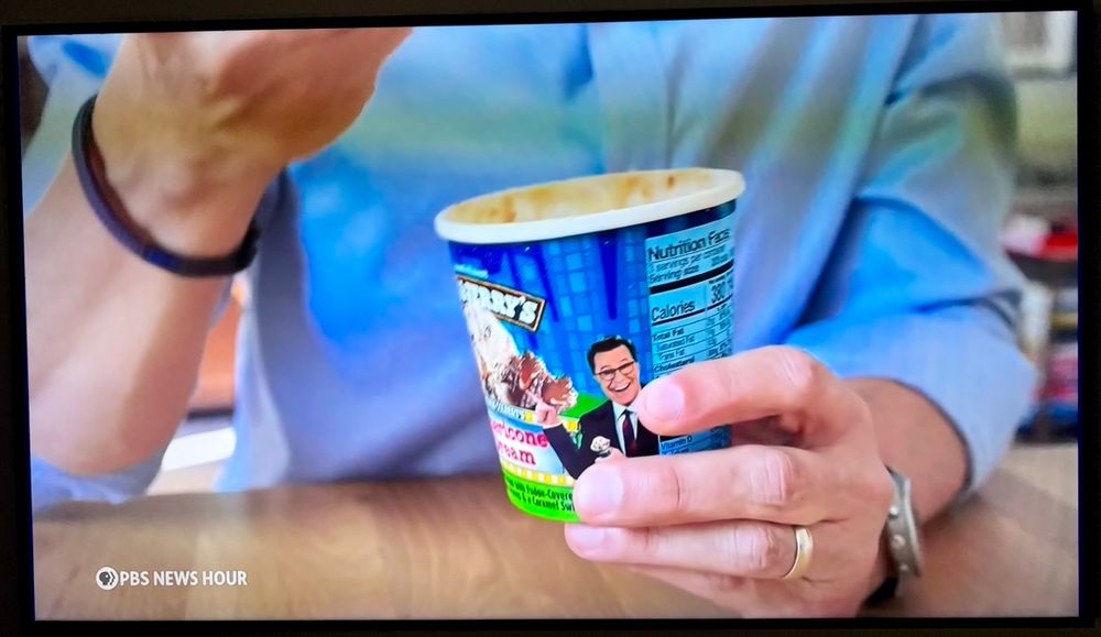 PBS NewsHour screenshot where William Bringham is eating Ben & Jerry’s American dream flavored ice cream by Stephen Colbert.