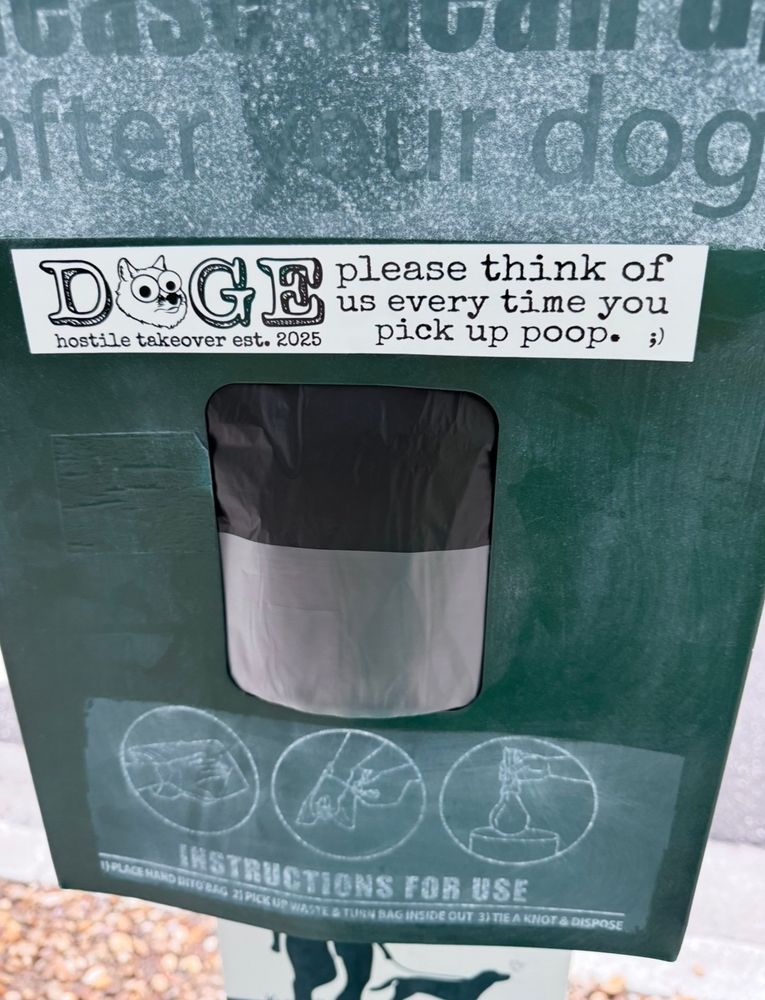 Sticker on a poop bag dispenser for dogs reads: DOGE (hostile takeover est. 2025) please think of us every time you pick up poop. ;)