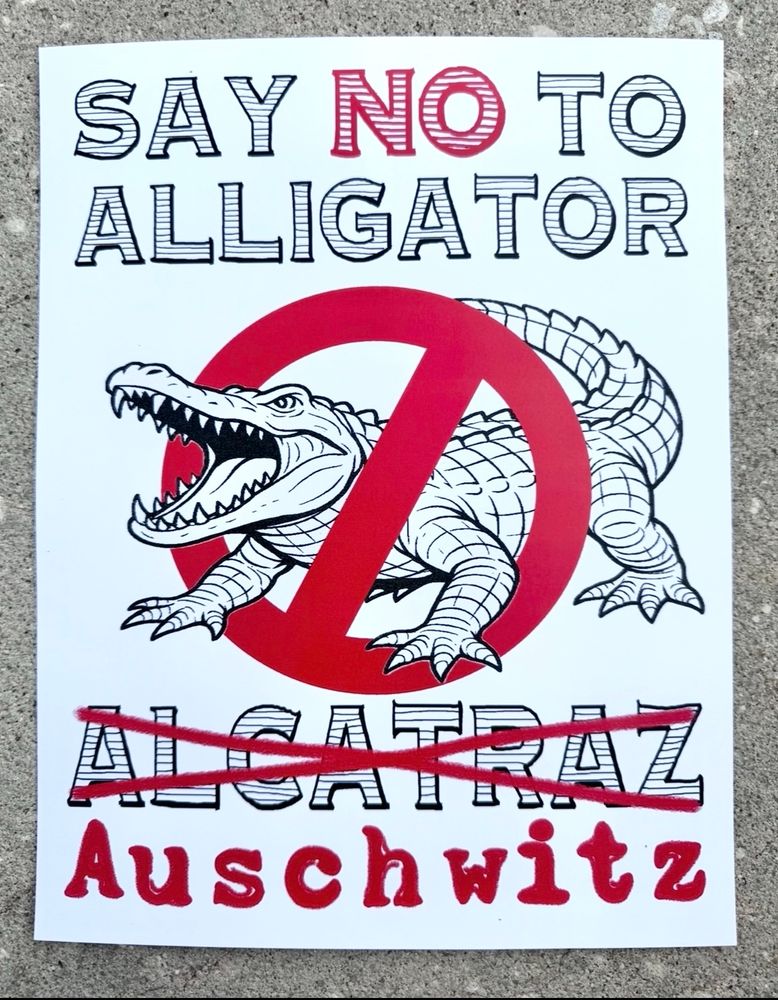 Sign has a picture of an alligator with a 🚫 over it.

Reads:

SAY NO TO ALLIGATOR
ALCATRAZ