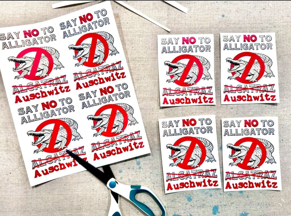 Sticker sheets have a picture of an alligator with a 🚫 over it.

Reads:

SAY NO TO ALLIGATOR
ALCATRAZ