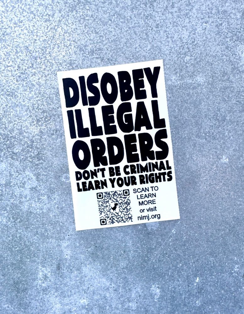 Sticker on metal wall reads: DISOBEY ILLEGAL ORDERS DON'T BE CRIMINAL LEARN YOUR RIGHTS SCAN TO LEARN MORE or visit nimj.org