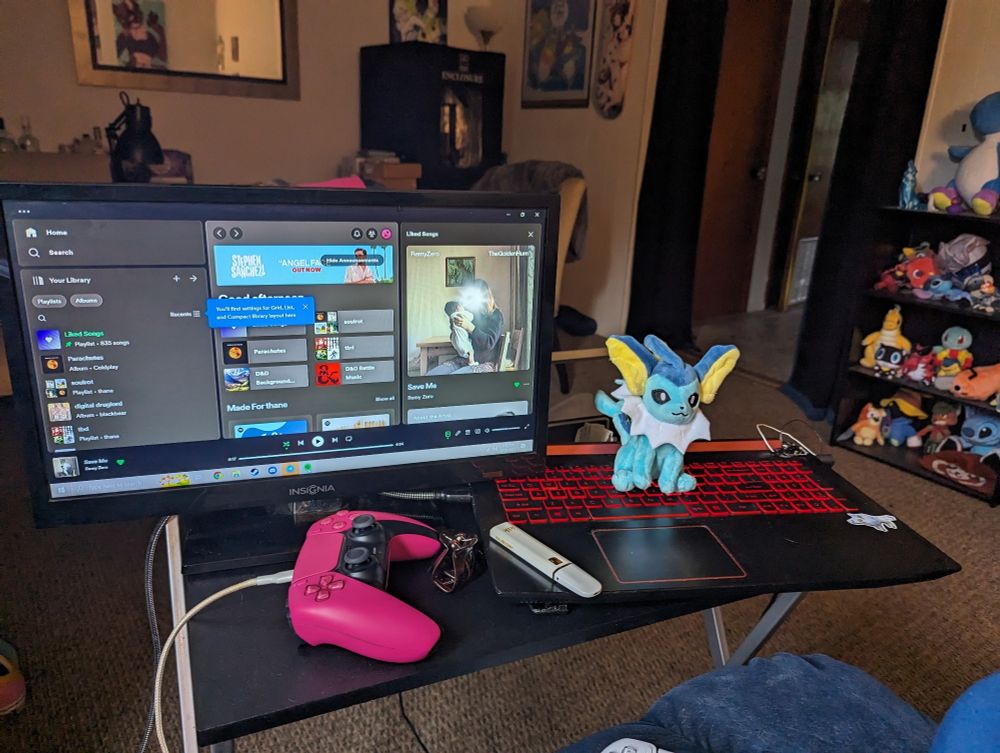 thane's sketchy-ass computer setup: a small TV monitor is plugged into the bottom half of a laptop on a small folding table. there is a vaporeon plushie sitting on the keyboard