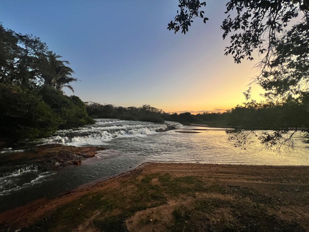 Cachoeira e rio durante o por do sol, com a mata preservada na margem