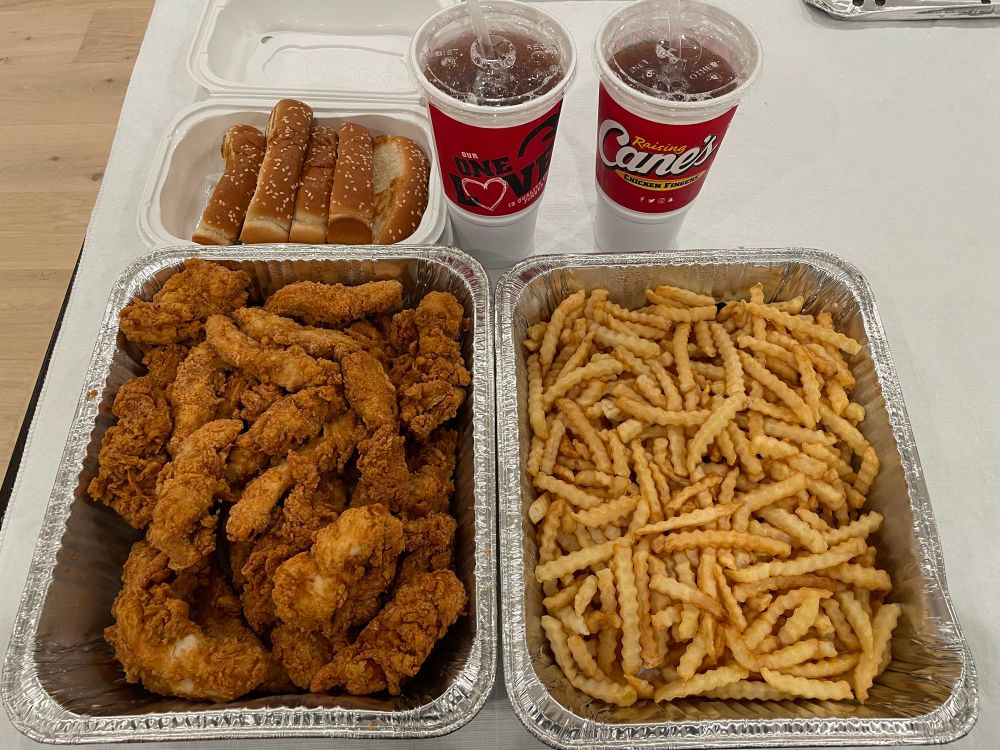 A party tray of 25 chicken fingers and an equivalent tray of fries from Raising Cane's, along with two large sweet teas and a box of Texas toast.