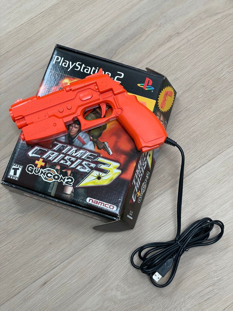 Namco Guncon2 light gun accessory for PlayStation 2 sitting on top of the box for Time Crisis 3 bundle.