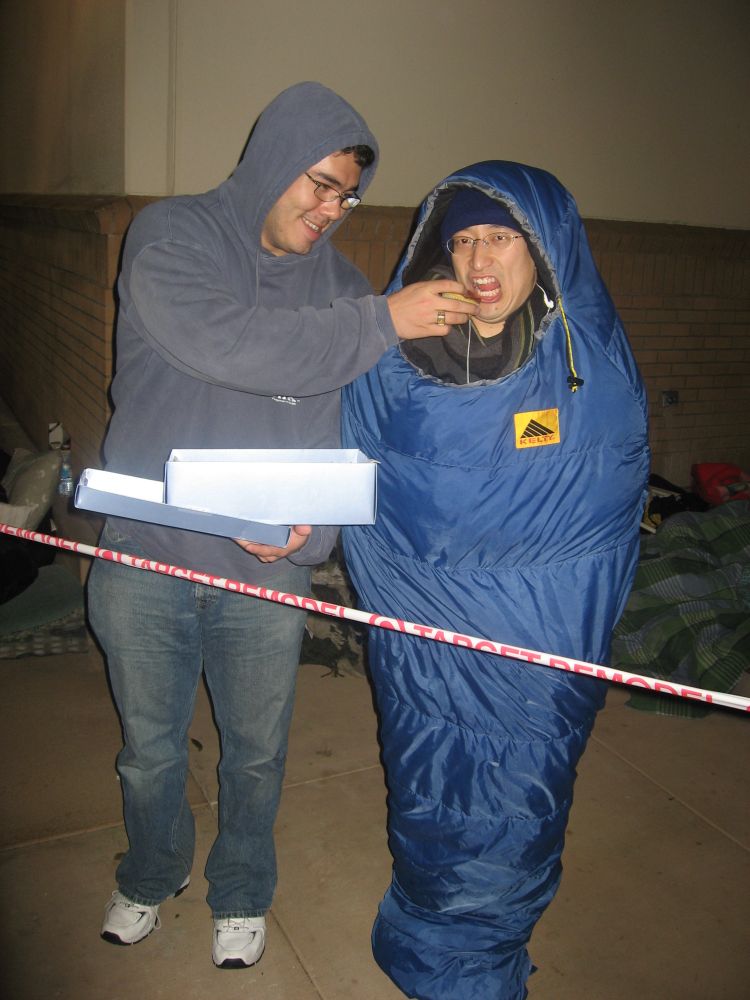 One nikkohunter feeds something to a luminpro encased in a blue sleeping bag, both camping out in front of a Target for Nintendo Wii launch.
