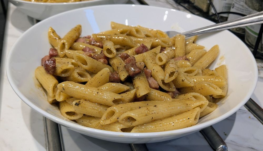 a glistening bowl of penne carbonara pasta, cooked by the boy what does cook