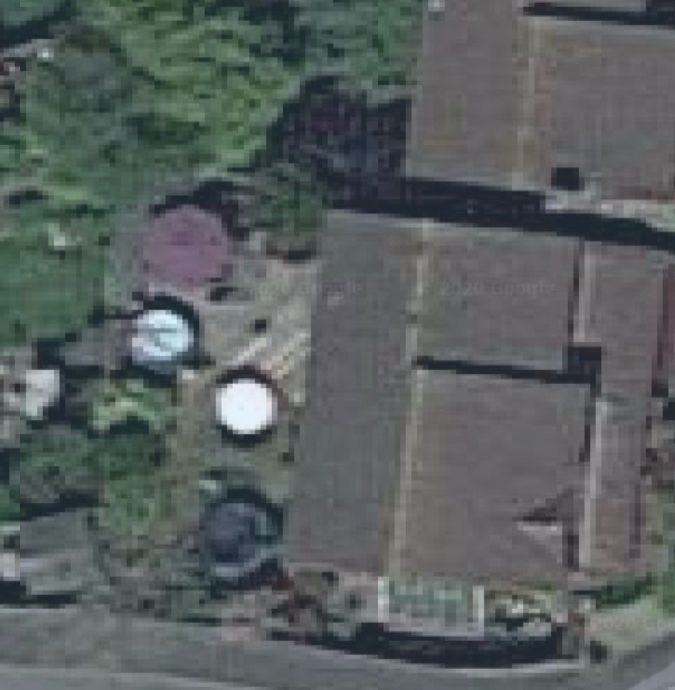 A screenshot from Google maps satellite view showing the faint image of a large man in a hot tub in his back garden