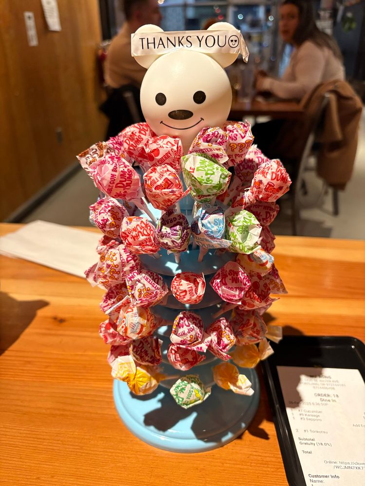 A lollipop tree containing dumdum pops and a sign on the top that says “Thanks you.” 