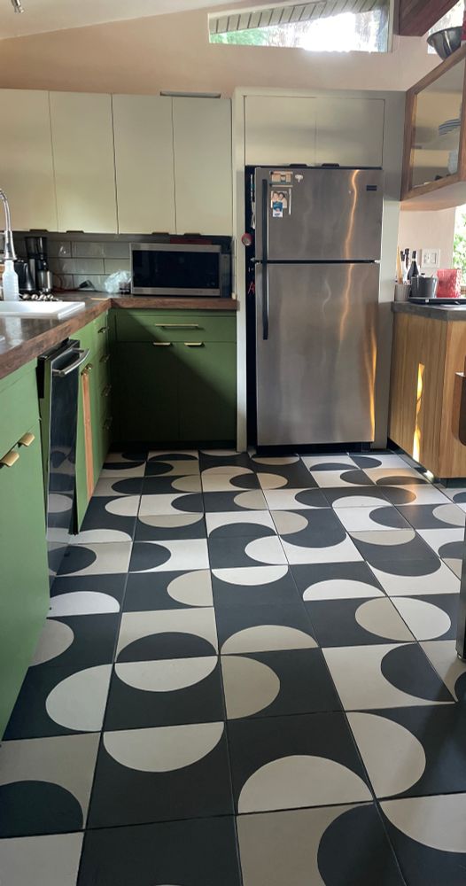 a kitchen with green cabinets and a multicolored tiled floor