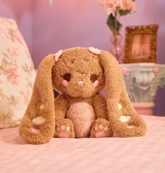 Cute brown and pink plush bunny on a pink bed