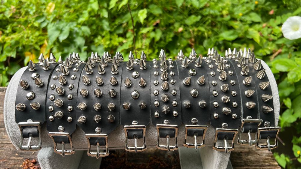 An assortment of black leather punk bracelets, some with silver studs and spikes, others with just spikes. They have buckles.