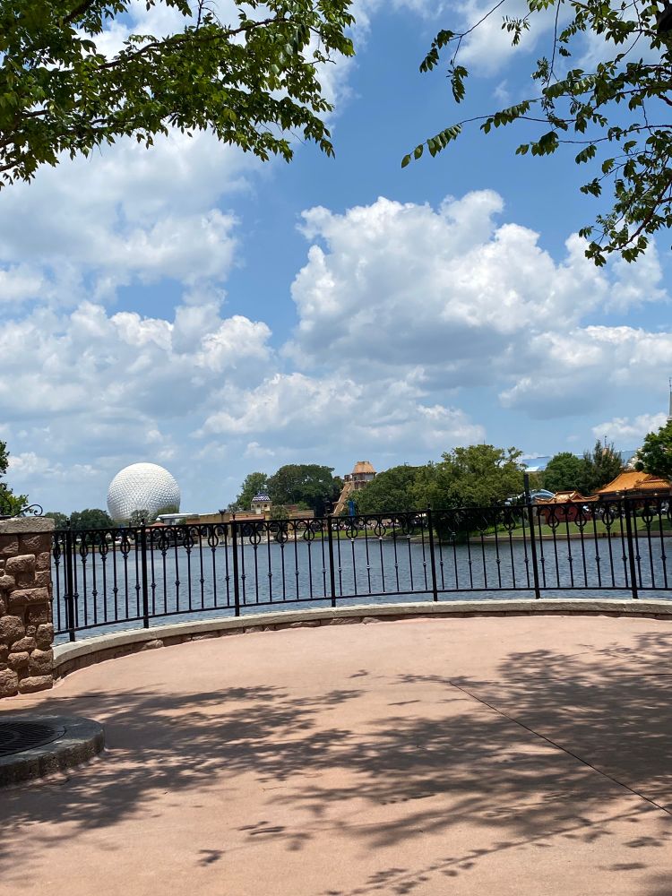 view of the Epcot sphere from across a lake, with tons of fluffy clouds in the sky 
