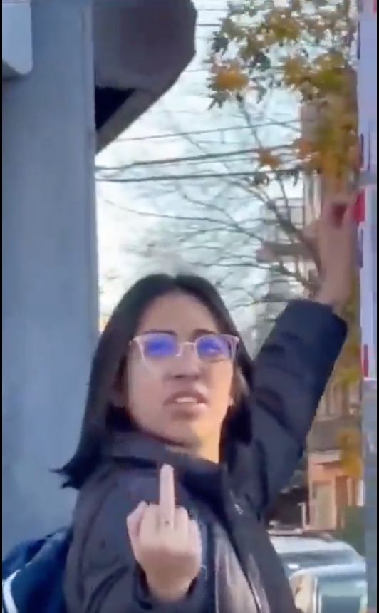 Une jeune femme arrachant une affiche fait un doigt d'honneur