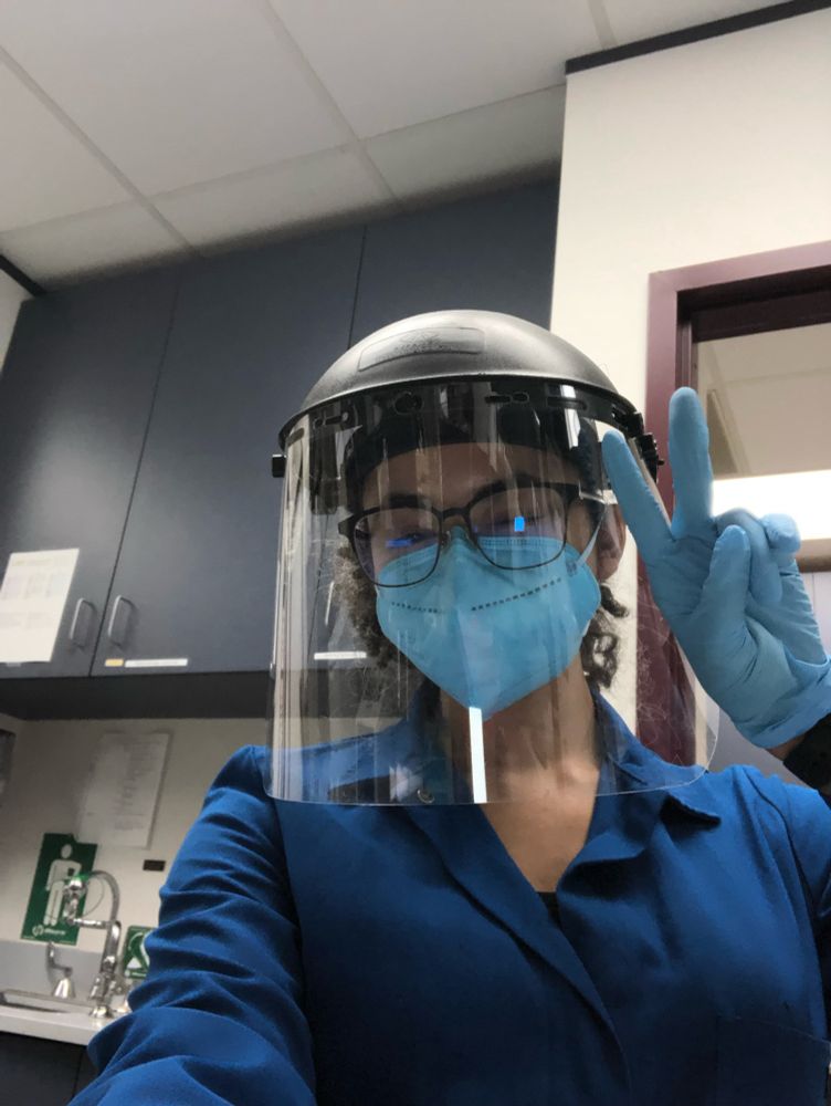 Me in full PPE (face shield, blue KN95 mask, gloves, and a lab coat). I’m giving a peace sign because idk how to pose for pictures.