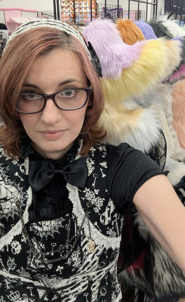 Me in casual Gothic Lolita in front of my booth full of fluffy tails