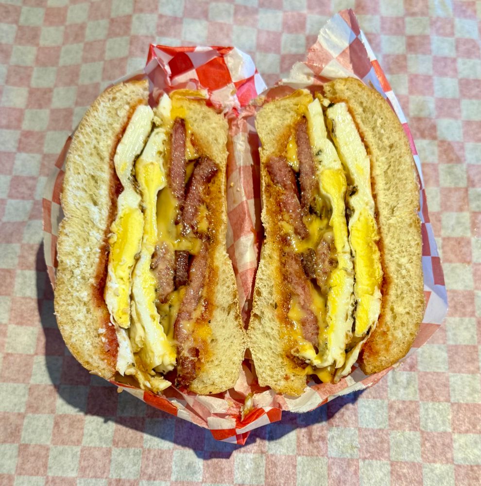 the sandwich is all wrapped up in red and white checkered paper and sliced in half to show the cross section 