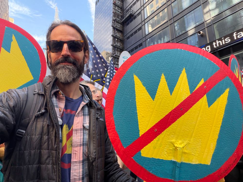 Bearded dude holding a No Kings sign. 