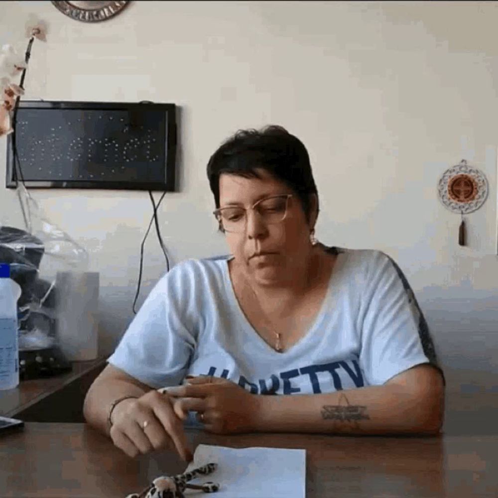 a woman is sitting at a table wearing a pretty shirt