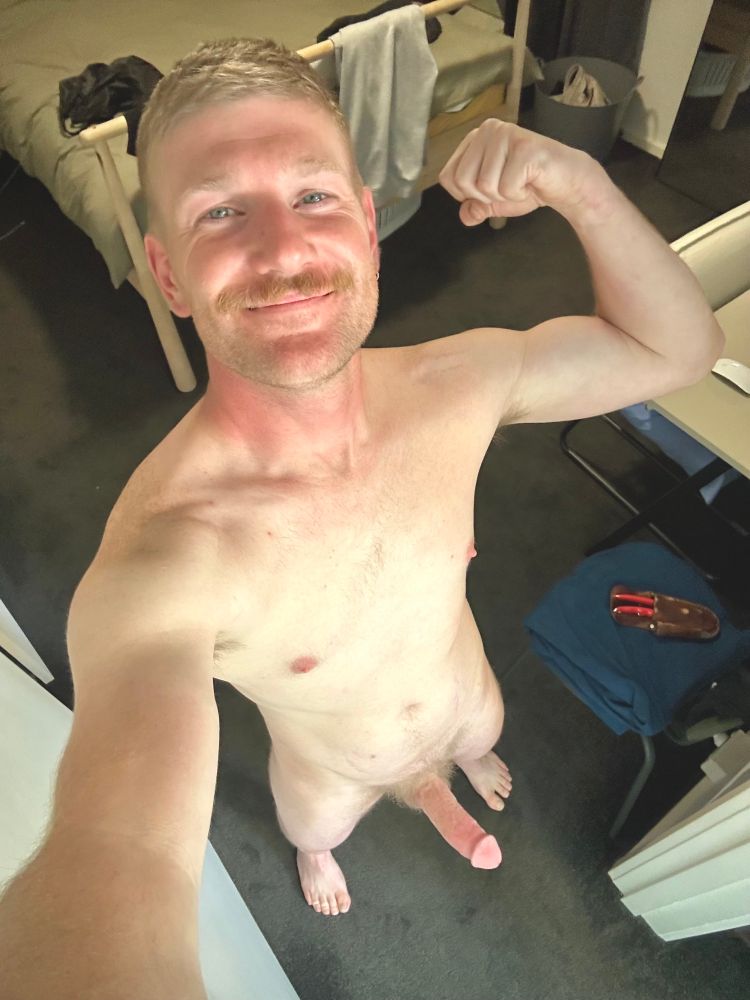 Selfie of a naked man flexing with a boner and smiling at the camera