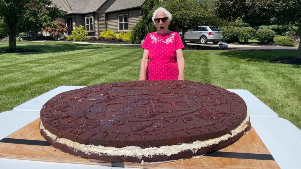 Grandma with her world's largest oreo cookie looking amazed at it on a sunny day.