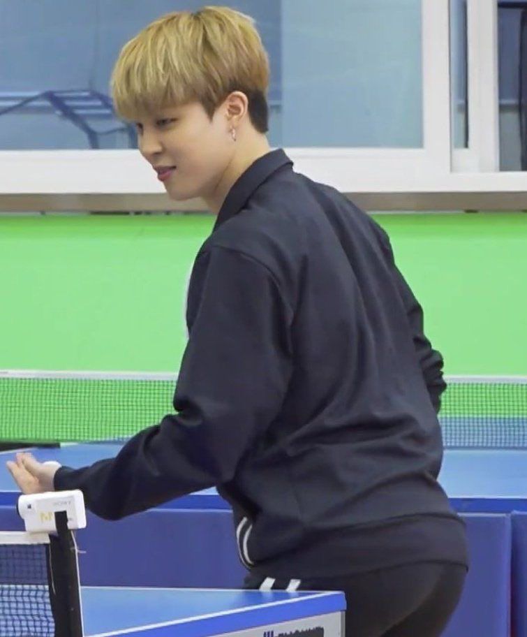 jimin with short blond hair wearing athletic clothes as he plays pingpong. his glorious ass on display.