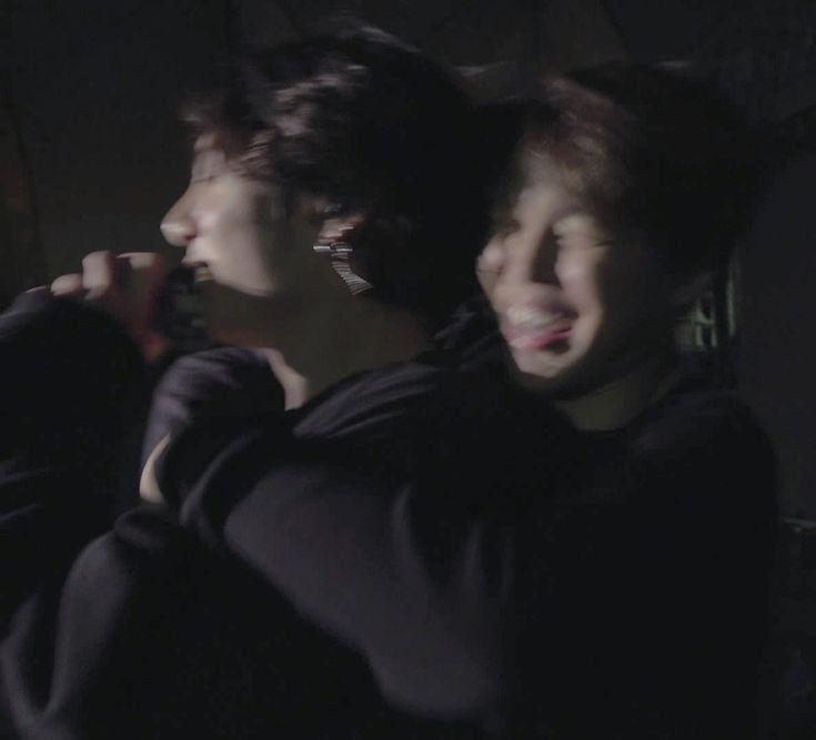 jungkook and jimin both in black. jungkook grins with a mic in his hand as jimin holds him, his tongue sticking out