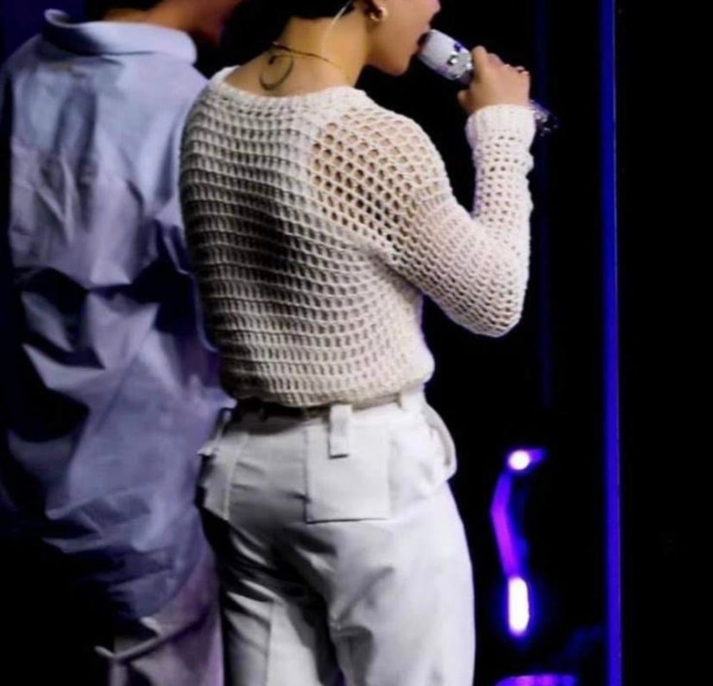 jimin in all white facing away from the camera, he has a mic in his hand and his glorious ass is on display.