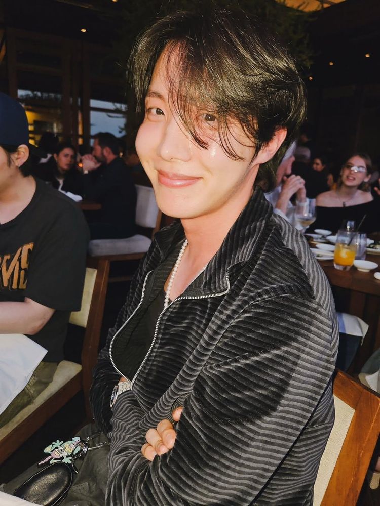 bro…where do i start… hoseok looking gorgeous with his long windswept hair and his arms crossed as he smiles into the camera. his cheeks glisten 