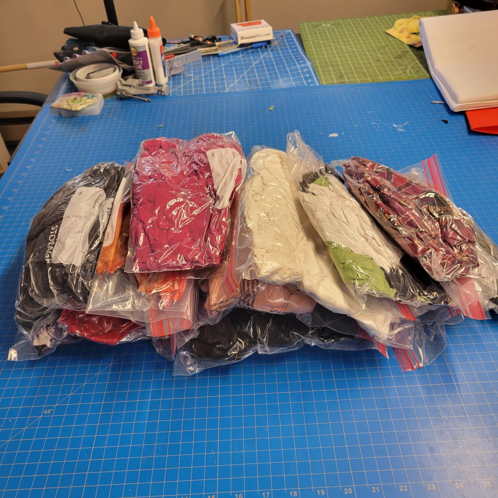 A stack of zipper bags containing fabric scraps.  They've been rolled and compressed to remove as much air as possible, so now all that fabric takes up considerably less volume 