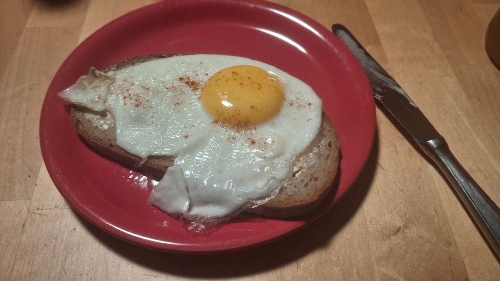 Ein Spiegelei auf Brot auf einem roten Teller