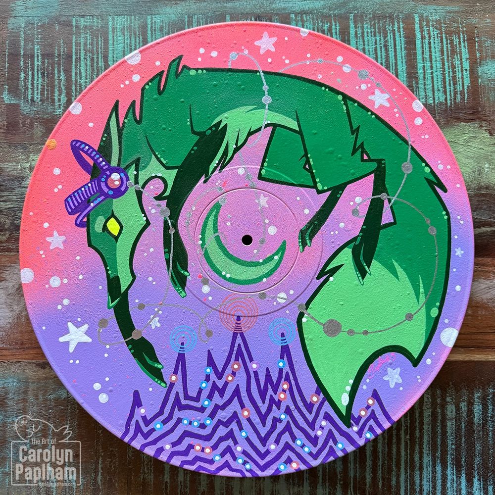 An acrylic marker drawing of a green fox wearing headphones, suspended in a sky full of stars and hovering over a green crescent moon. Jagged lines ripple outward at the bottom, reminiscent of jagged sound waves. The drawing was done on a vinyl record.