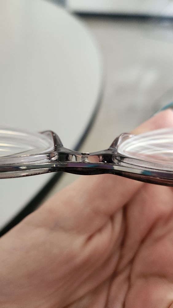 Top view of a pair of glasses with a screw poking out as it's not laying flush. 