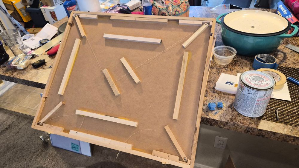 Inside of a drafting board. There is rubber cement to the side of it on the counter. The bottom right corner has two pieces with wet glue being reattached. 